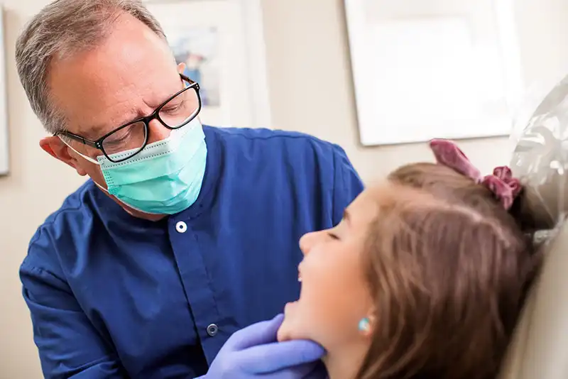 Dr-with-mask-looking-at-childs-mouth Dr. William Parr examining child Pediatric Dentistry