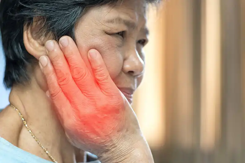 TMJ Photo for Parr dental TMJ & Jaw Disorders Asian woman with pain in cheek and irritation on hand