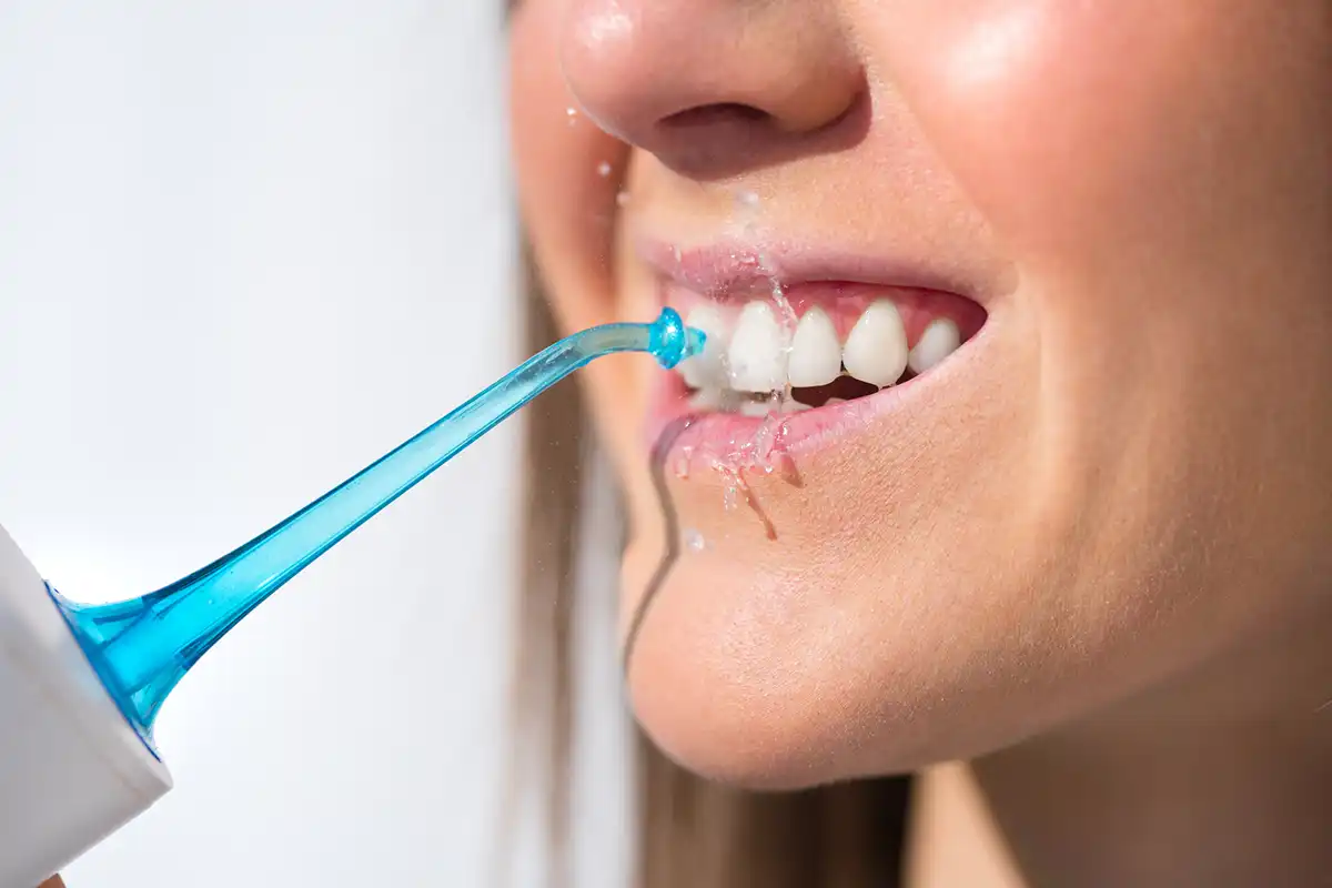 Unlocking the power of water flossers with picture of patient wateer flossing their teeth.