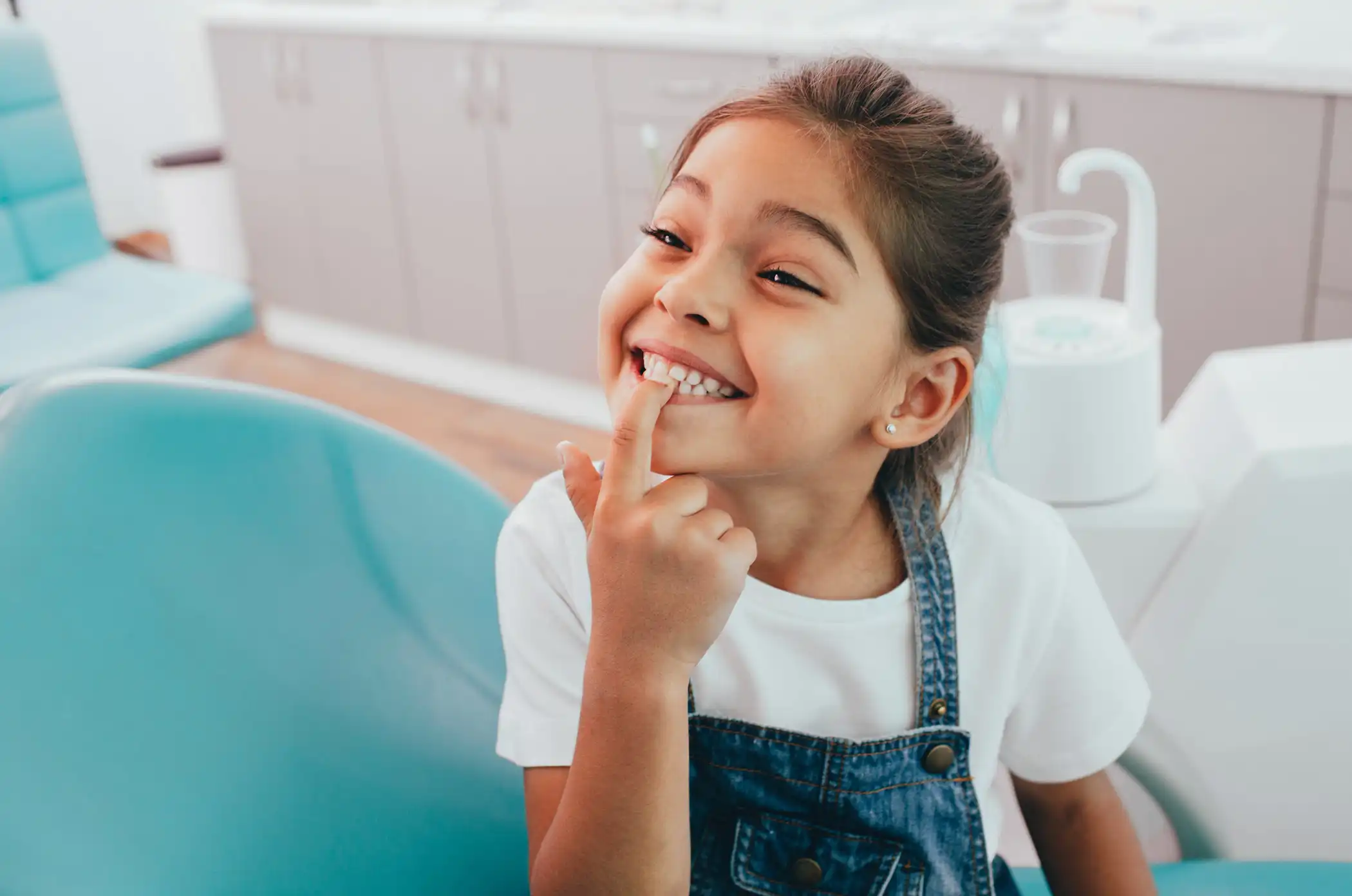 Little girl pointing a finger at her tooth.